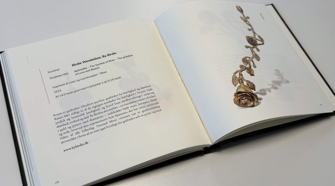 Åben bog med tekst om rosen-inspireret smykke.